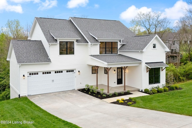 view of front of property with a front yard, a garage, and a porch