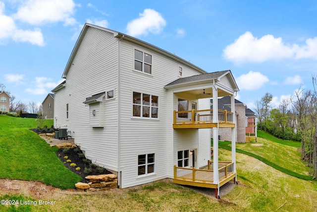 rear view of property with ceiling fan, cooling unit, a yard, a wooden deck, and a balcony