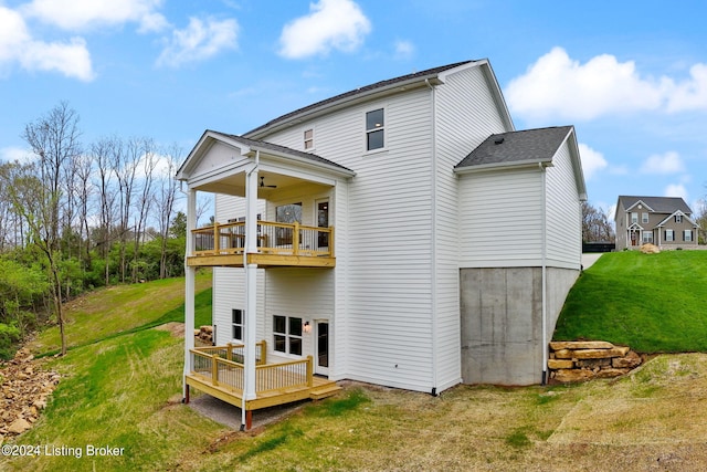 rear view of house with ceiling fan, a deck, a balcony, and a yard