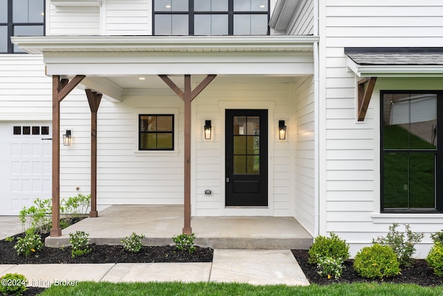 doorway to property featuring a porch and a garage