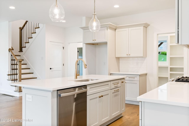 kitchen with pendant lighting, dishwasher, white cabinetry, sink, and a kitchen island with sink