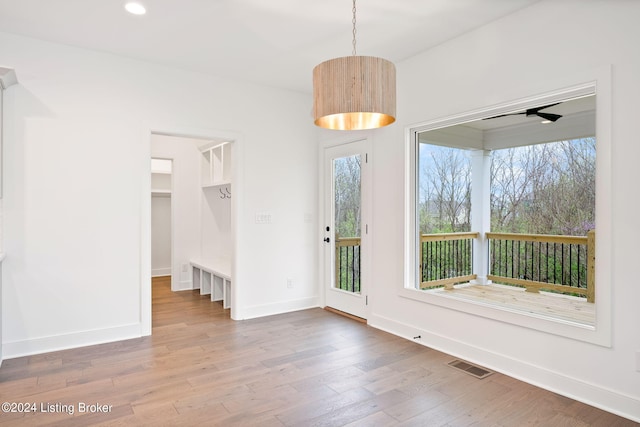 unfurnished dining area featuring ceiling fan, wood-type flooring, and plenty of natural light