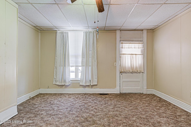 carpeted empty room with a wealth of natural light, ceiling fan, and a paneled ceiling