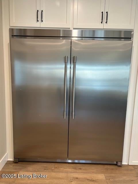 details featuring stainless steel built in fridge, white cabinetry, and light hardwood / wood-style flooring