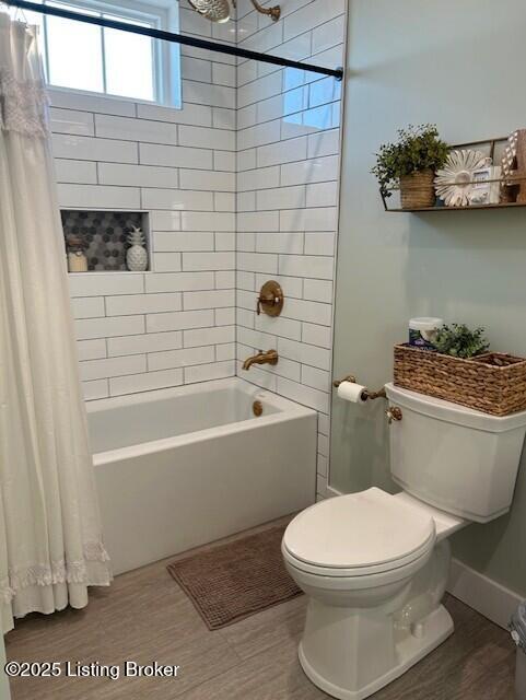 bathroom featuring hardwood / wood-style flooring, toilet, and shower / bathtub combination with curtain