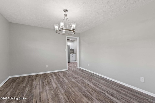 unfurnished room with an inviting chandelier, dark hardwood / wood-style floors, and a textured ceiling