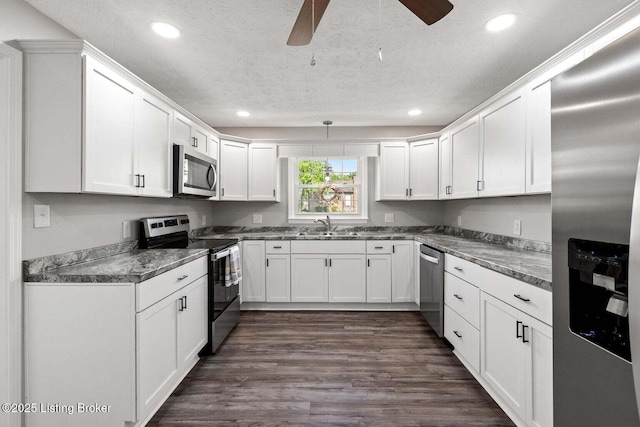 kitchen with sink, dark wood-type flooring, white cabinets, and appliances with stainless steel finishes