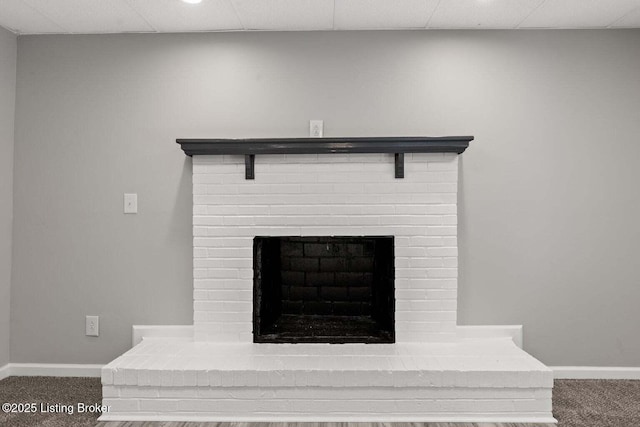 room details featuring carpet, a drop ceiling, and a fireplace