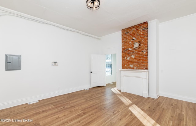 unfurnished living room with electric panel, ornamental molding, and light wood-type flooring