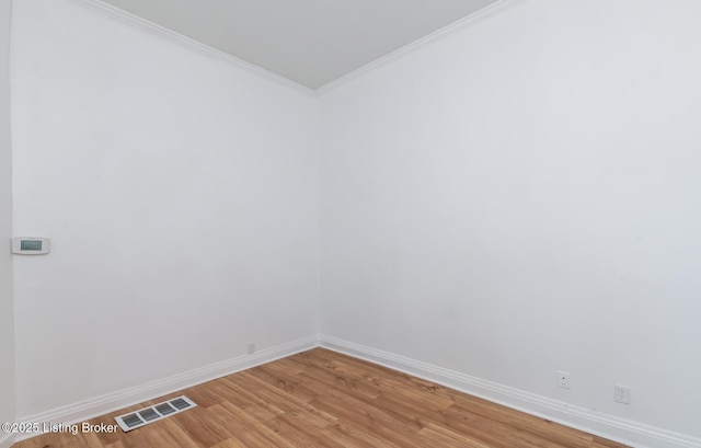 empty room featuring wood-type flooring and ornamental molding