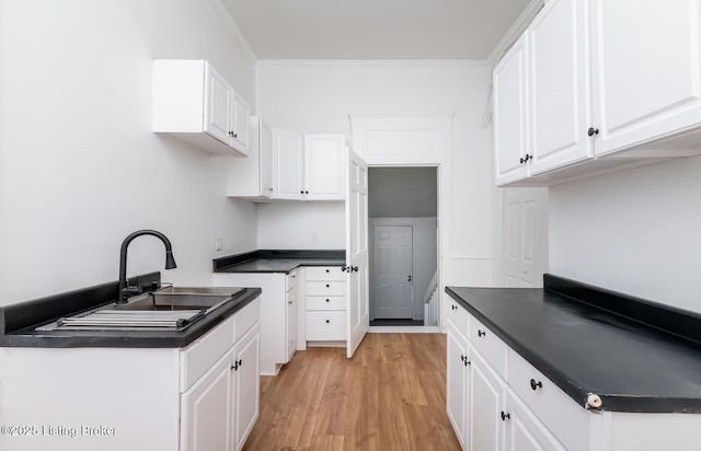 kitchen featuring sink, white cabinets, light hardwood / wood-style floors, and crown molding