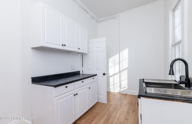 kitchen with sink, white cabinets, crown molding, and light wood-type flooring