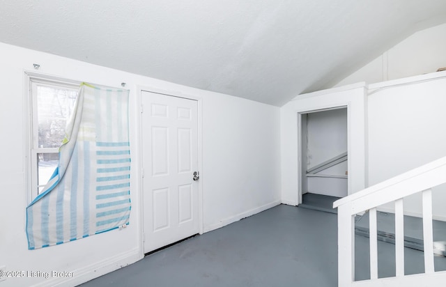 additional living space featuring a textured ceiling and lofted ceiling