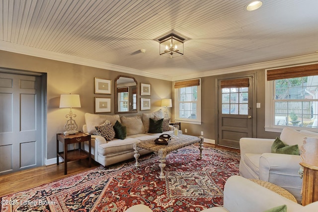 living room with hardwood / wood-style flooring, ornamental molding, and an inviting chandelier