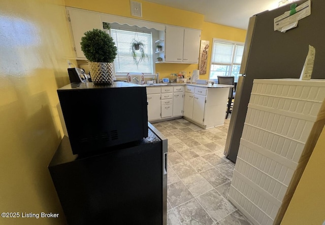 kitchen with plenty of natural light, white cabinets, and sink