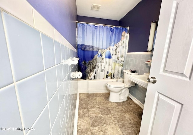 bathroom featuring shower / bath combo with shower curtain, tile walls, and toilet