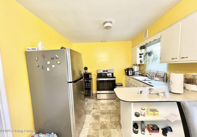 kitchen featuring white cabinets, kitchen peninsula, appliances with stainless steel finishes, and sink