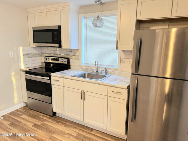 kitchen with pendant lighting, sink, white cabinetry, stainless steel appliances, and light stone counters