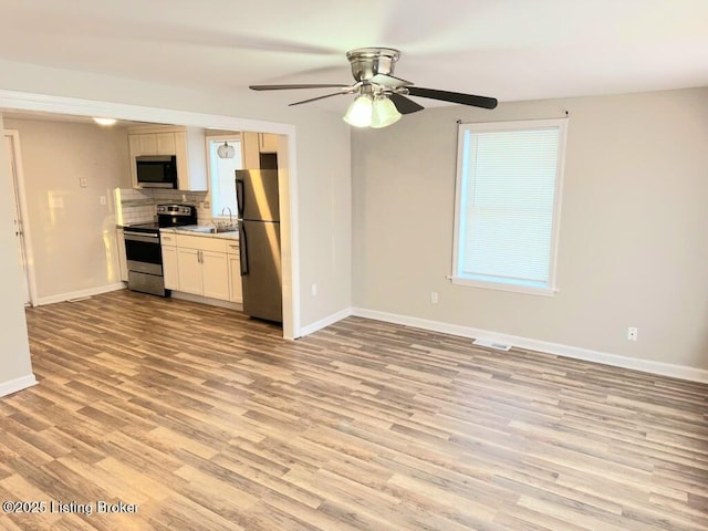 unfurnished living room with ceiling fan, sink, and light hardwood / wood-style flooring