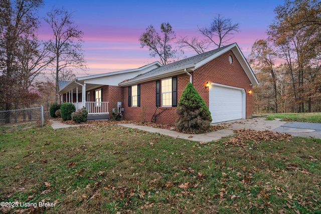 ranch-style home featuring a yard, covered porch, and a garage