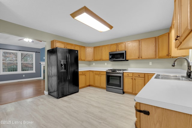 kitchen featuring light brown cabinets, stainless steel appliances, light hardwood / wood-style floors, sink, and ceiling fan