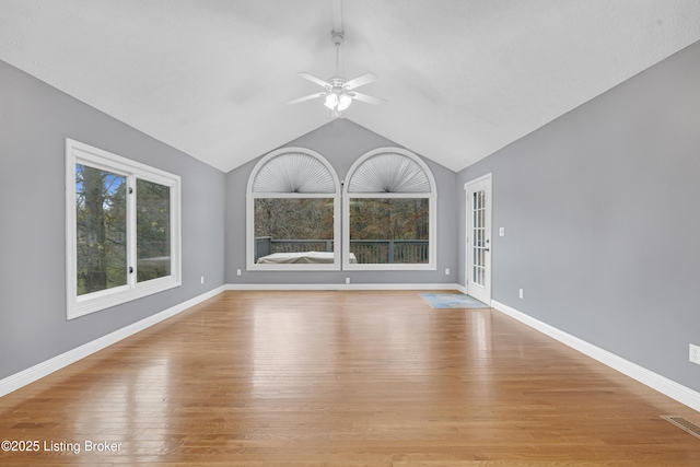 unfurnished living room with vaulted ceiling, ceiling fan, light hardwood / wood-style flooring, and french doors