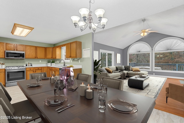 dining space featuring ceiling fan with notable chandelier, sink, lofted ceiling, and light hardwood / wood-style floors