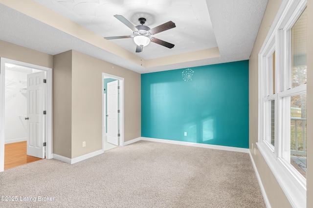 carpeted spare room with ceiling fan and a raised ceiling