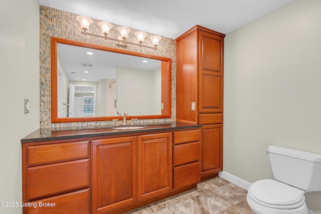 bathroom with toilet, vanity, and tasteful backsplash