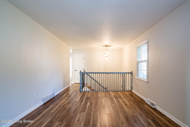 empty room featuring dark wood-type flooring and a textured ceiling