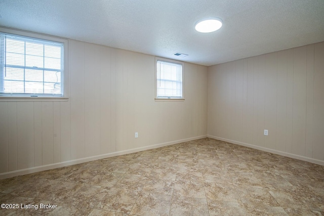 unfurnished room featuring wood walls and a textured ceiling