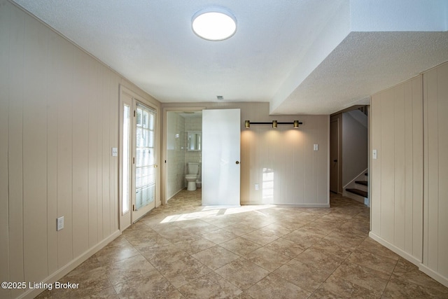 foyer entrance with a textured ceiling, a barn door, and wooden walls