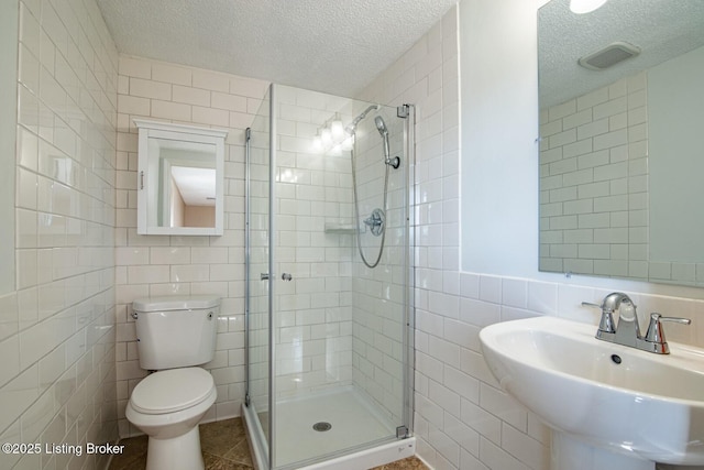 bathroom featuring toilet, tile walls, walk in shower, and sink