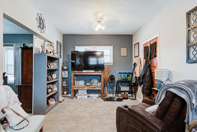 living room featuring a textured ceiling, ceiling fan, and carpet