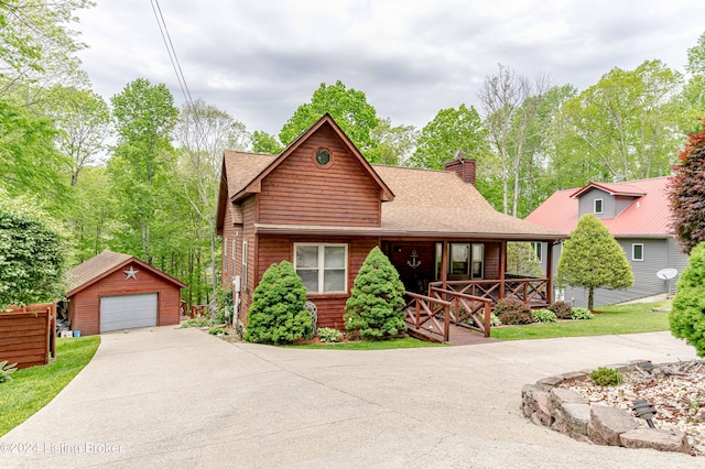 view of front of property featuring a garage, a porch, and an outdoor structure