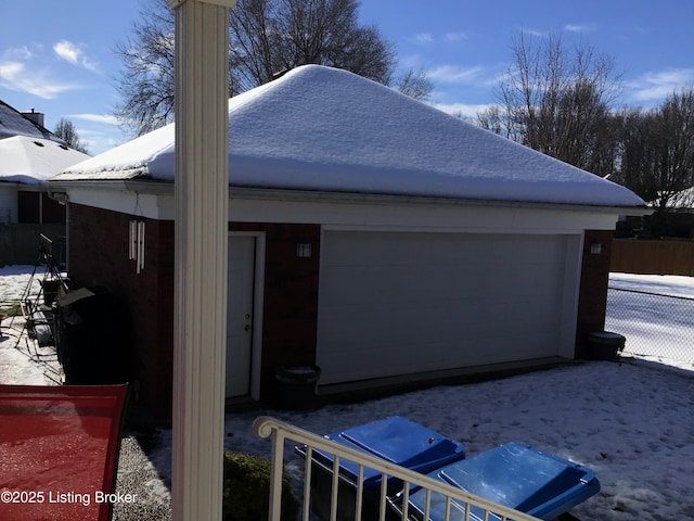 view of snow covered exterior featuring an outbuilding and a garage