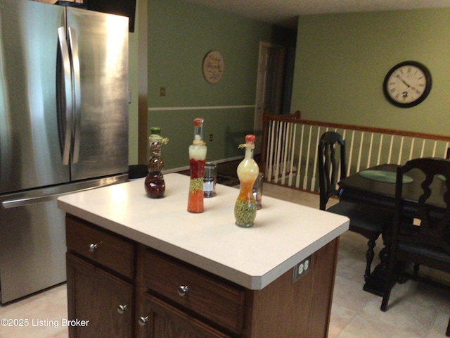 kitchen with a kitchen island, dark brown cabinets, and stainless steel refrigerator