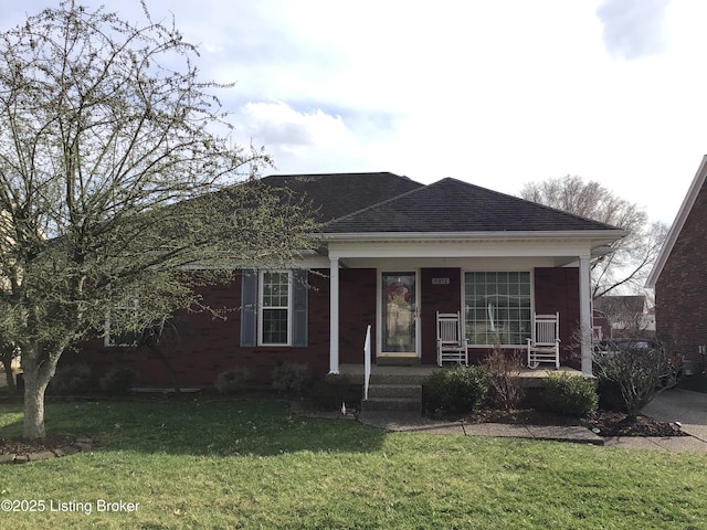 view of front of home featuring roof with shingles, a porch, and a front yard