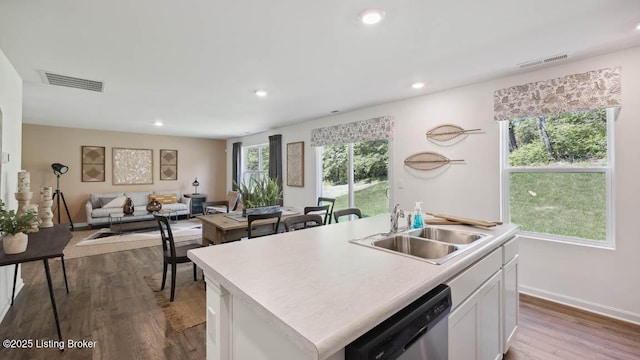 kitchen featuring white cabinetry, hardwood / wood-style flooring, a center island with sink, dishwasher, and sink