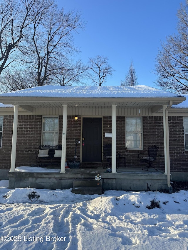 snow covered property entrance with a porch