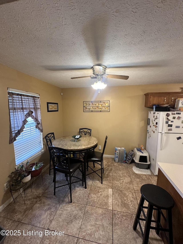 dining room featuring a textured ceiling, ceiling fan, and light tile patterned floors