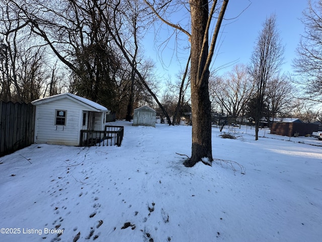 snowy yard featuring a storage shed