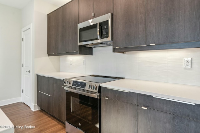 kitchen featuring light countertops, light wood-type flooring, dark brown cabinetry, and stainless steel appliances