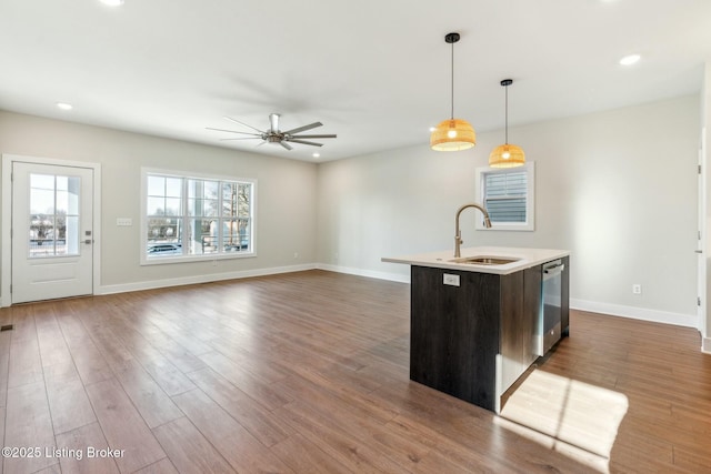 kitchen featuring stainless steel dishwasher, dark wood-type flooring, light countertops, and a sink