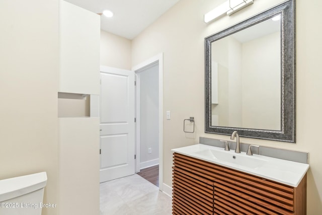 bathroom with baseboards, toilet, and vanity