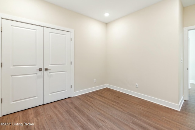 unfurnished bedroom featuring recessed lighting, light wood-type flooring, baseboards, and a closet