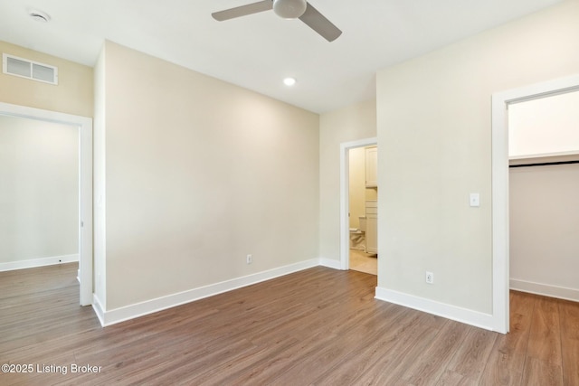 unfurnished bedroom with baseboards, visible vents, light wood finished floors, a spacious closet, and a closet