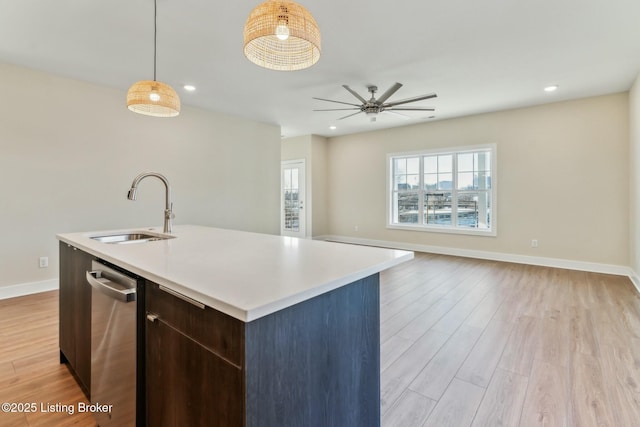 kitchen with baseboards, a sink, light countertops, light wood-style floors, and stainless steel dishwasher