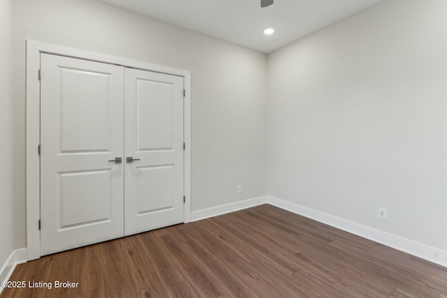 unfurnished bedroom with recessed lighting, a closet, baseboards, and wood finished floors