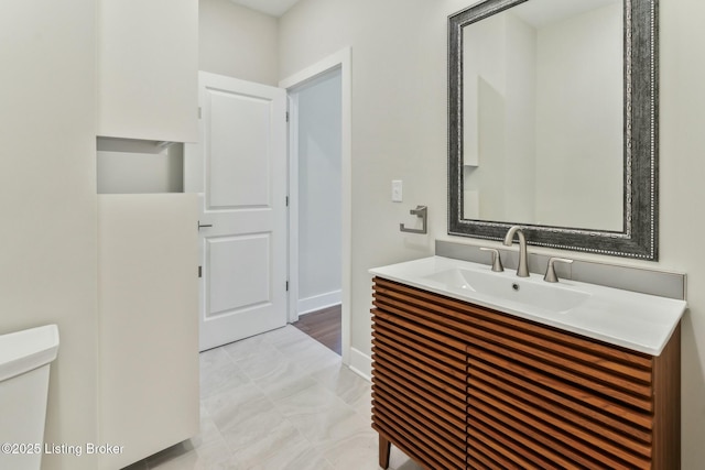 bathroom featuring vanity, toilet, and baseboards